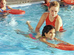 Safety instructor teaching a child to swim